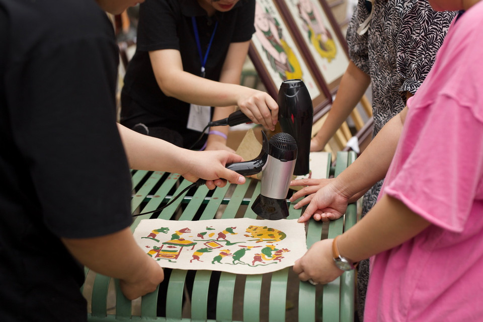 Sau khi in màu, các bức tranh sẽ được các thành viên trong ban tổ chức sấy khô. (Ảnh: Đặng Yến/Vietnam+)