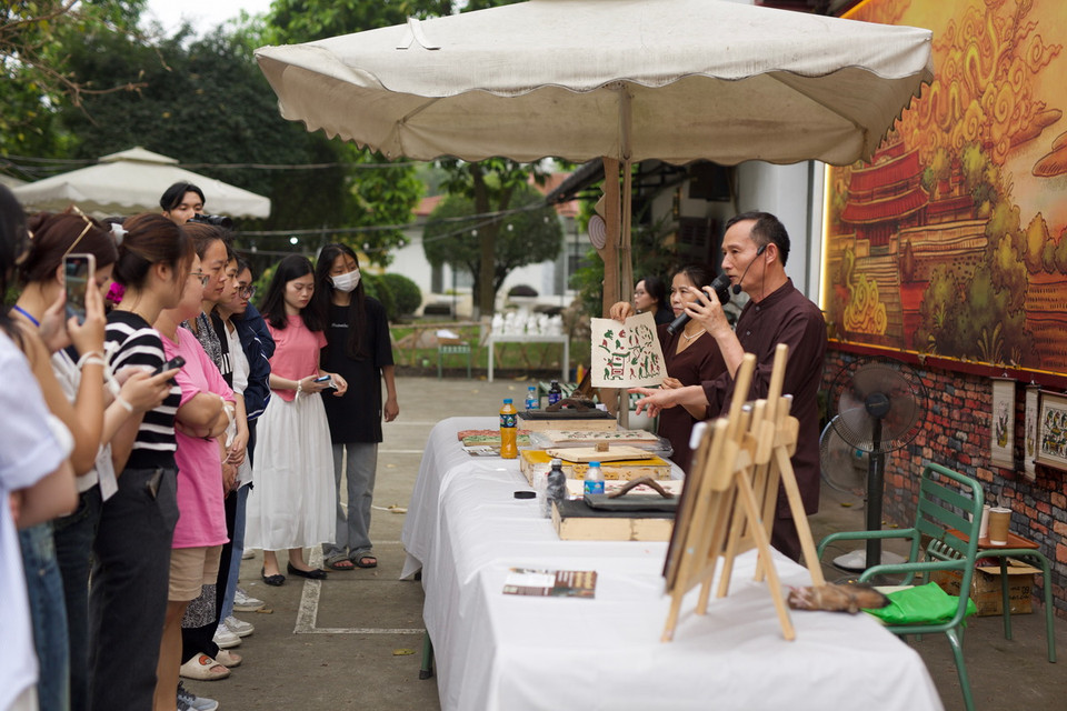 Nghệ nhân Nguyễn Hữu Quả phát biểu khai mạc workshop và chia sẻ quy trình làm tranh cho đến những câu chuyện về quá trình thăng trầm của dòng tranh này. (Ảnh: Đặng Yến/Vietnam+)