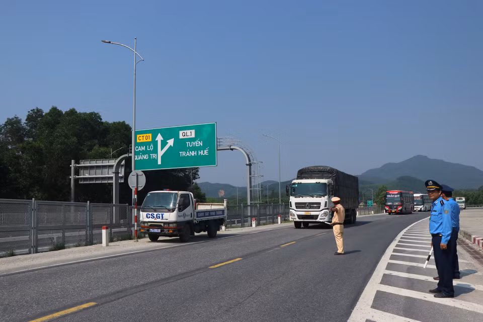 Các lực lượng thực hiện công tác hướng dẫn, điều tiết các phương tiện chấp hành phương án phân luồng tại lối vào cao tốc Cam Lộ-La Sơn ở nút giao cầu Tuần. (Ảnh: Nguyên Lý/TTXVN)