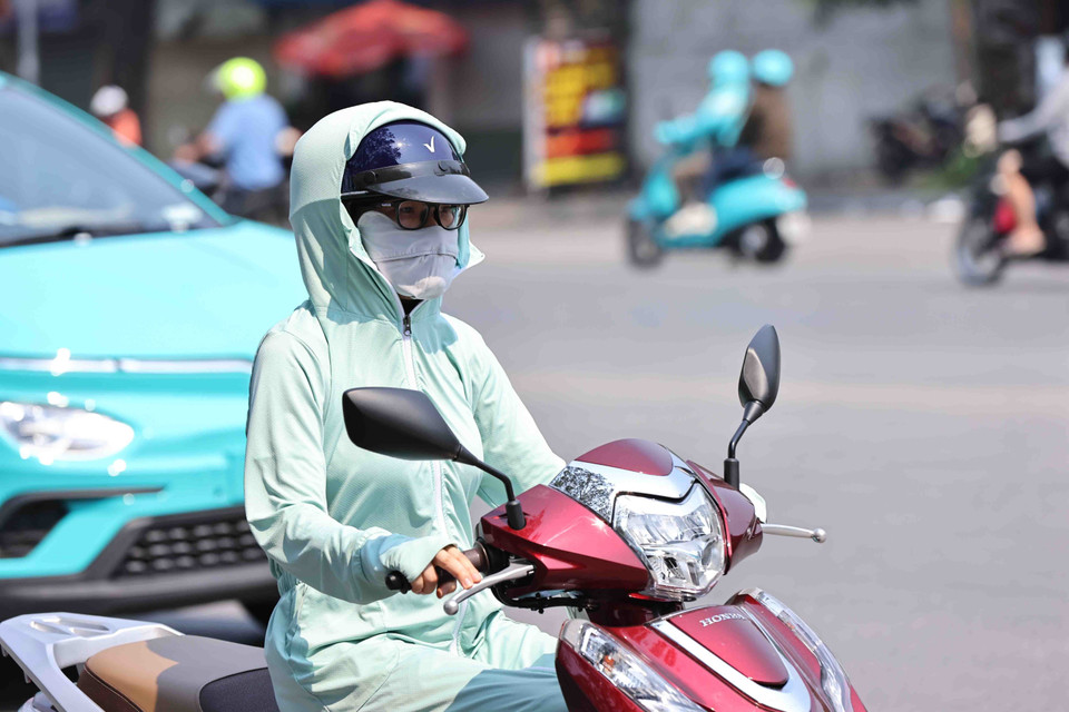 Mỗi khi phải ra đường, dù người lớn hay trẻ em đều dùng mọi biện pháp như khẩu trang hay áo chống nắng để chống lại cái nắng nóng gay gắt. (Ảnh: Minh Đức/TTXVN)