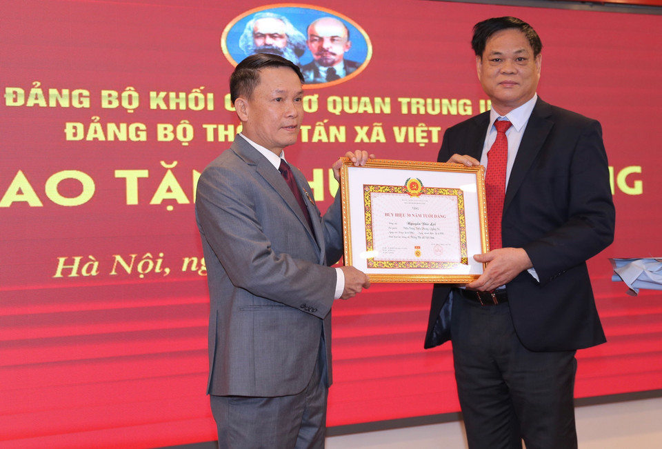 Ông Huỳnh Tấn Việt, Ủy viên Trung ương Đảng, Bí thư Đảng ủy Khối các cơ quan Trung ương trao Huy hiệu 30 năm tuổi Đảng cho ông Nguyễn Đức Lợi, Ủy viên Trung ương Đảng, Tổng Giám đốc TTXVN. (Ảnh: Hoàng Hiếu/TTXVN)