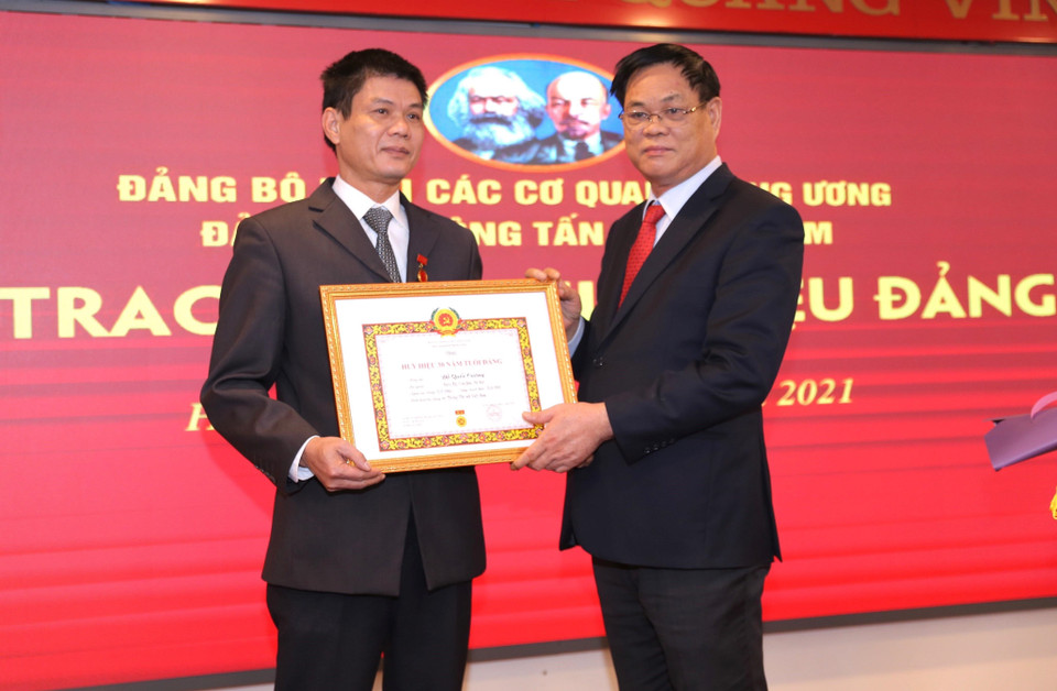 Ủy viên Trung ương Đảng, Bí thư Đảng ủy Khối các cơ quan Trung ương Huỳnh Tấn Việt trao Huy hiệu 30 năm tuổi Đảng cho ông Đỗ Quốc Cường đảng viên Đảng bộ cơ sở Văn phòng, Đảng bộ TTXVN. (Ảnh: Hoàng Hiếu/TTXVN)