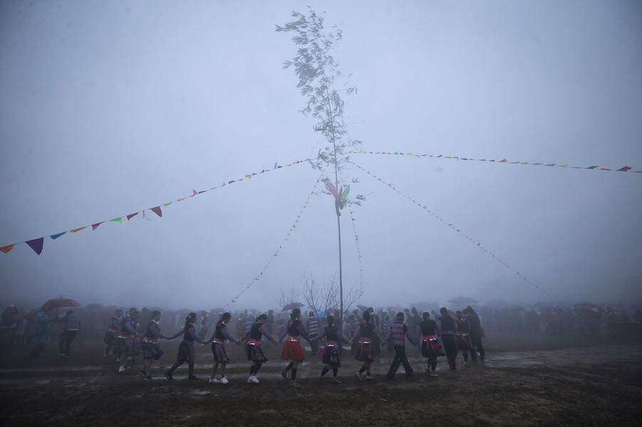 Các chàng trai, cô gái Mông cùng du khách nắm tay nhau nhảy múa theo tiếng khèn xung quanh cây nêu. (Ảnh: Trọng Đạt/TTXVN)