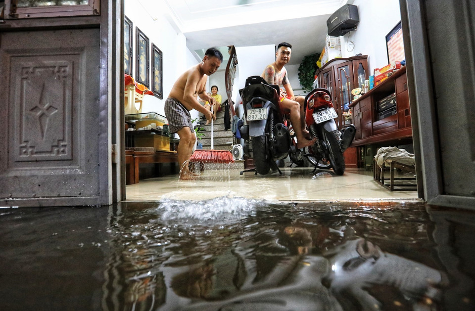 1 hộ gia đình ngõ 90, phố Đội Cấn (Hà Nội) tát nước từ trong nhà ra sau cơn mưa lớn tối 22/6. (Ảnh: Thành Đạt/TTXVN)