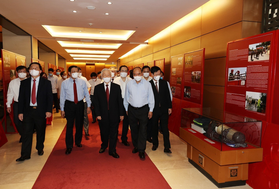 Sáng 12/6/2021, tại Hà Nội, Ban Bí thư Trung ương Đảng tổ chức Hội nghị sơ kết 5 năm thực hiện Chỉ thị số 05-CT/TW của Bộ Chính trị khóa XII, triển khai Kết luận số 01-KL/TW của Bộ Chính trị khóa XIII về tiếp tục thực hiện Chỉ thị số 05-CT/TW 'Về đẩy mạnh học tập và làm theo tư tưởng, đạo đức, phong cách Hồ Chí Minh' và Hội nghị nghiên cứu, học tập chuyên đề toàn khóa nhiệm kỳ Đại hội XIII của Đảng - chuyên đề năm 2021. Trong ảnh: Tổng Bí thư Nguyễn Phú Trọng, Chủ tịch nước Nguyễn Xuân Phúc, Thường trực Ban Bí thư Võ Văn Thưởng và các đại biểu thăm Triển lãm Những tấm gương bình dị mà cao quý trưng bày bên sảnh hội nghị. (Ảnh: Trí Dũng/TTXVN)