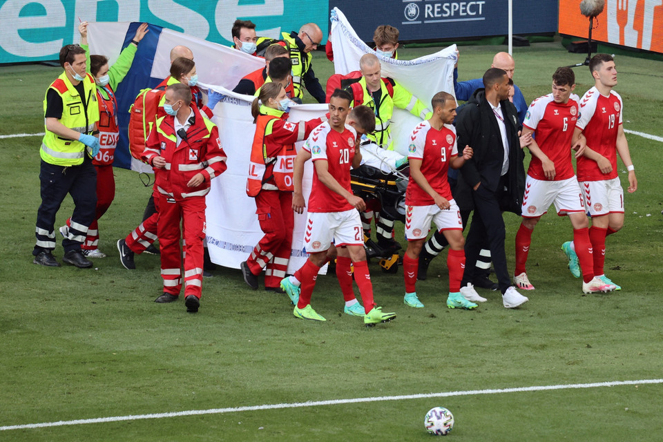 Các tuyển thủ Đan Mạch hỗ trợ nhân viên y tế chuyển tiền vệ Christian Erikssen rời sân khi anh bất ngờ ngã gục trong trận gặp đội Phần Lan ở bảng B. (Ảnh: AFP/TTXVN)