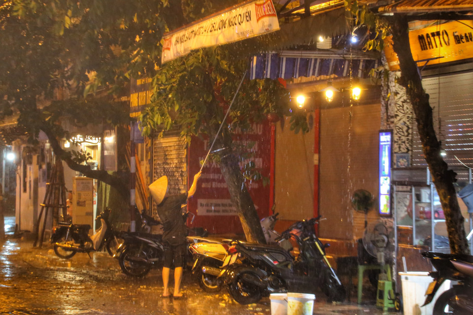 Mưa to kèm gió giật mạnh khiến người dân phải gia cố lại bạt che. (Ảnh: Tuấn Đức/TTXVN)