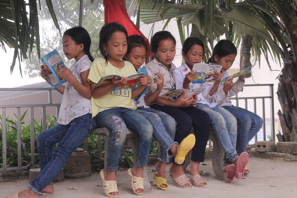 Học sinh trường Tiểu học Huồi Tụ 2 đọc sách mượn tại Tủ sách học đường. (Ảnh: Bích Huệ/TTXVN)
