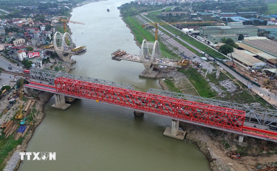 Bên cạnh đó cầu đường sắt (màu đỏ) bắc qua sông Đuống cũng được nhà thầu thi công khẩn trương. Sau khi hoàn thành đường bộ và đường sắt qua sông Đuống tách bạch. (Ảnh: Quốc Khánh/TTXVN)