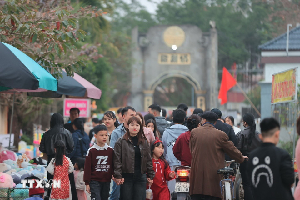 Người đi bộ, người đi xe, tay xách nách mang, ai cũng rạng rỡ trong bộ quần áo mới, ánh mắt ánh lên niềm vui đầu năm. (Ảnh: Minh Quyết/TTXVN)