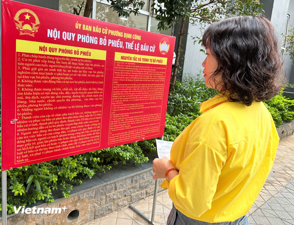 Cử tri tại khu vực bỏ phiếu số 4, phường Định Công, Hà Nội nghiên cứu Nội quy phòng bỏ phiếu, thể lệ bầu cử. (Ảnh: Trí Đức/Vietnam+)