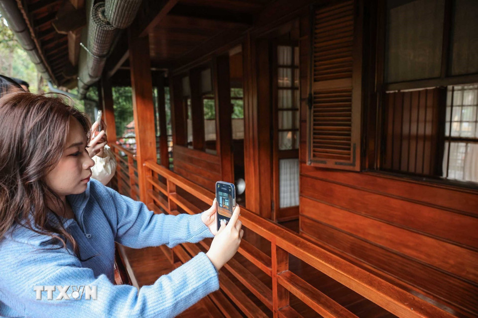 Người dân ghi lại kỷ niệm khi được thăm Nhà sàn Bác Hồ nằm trong khu di tích Chủ tịch Hồ Chí Minh. (Ảnh: Hoàng Hiếu/TTXVN)