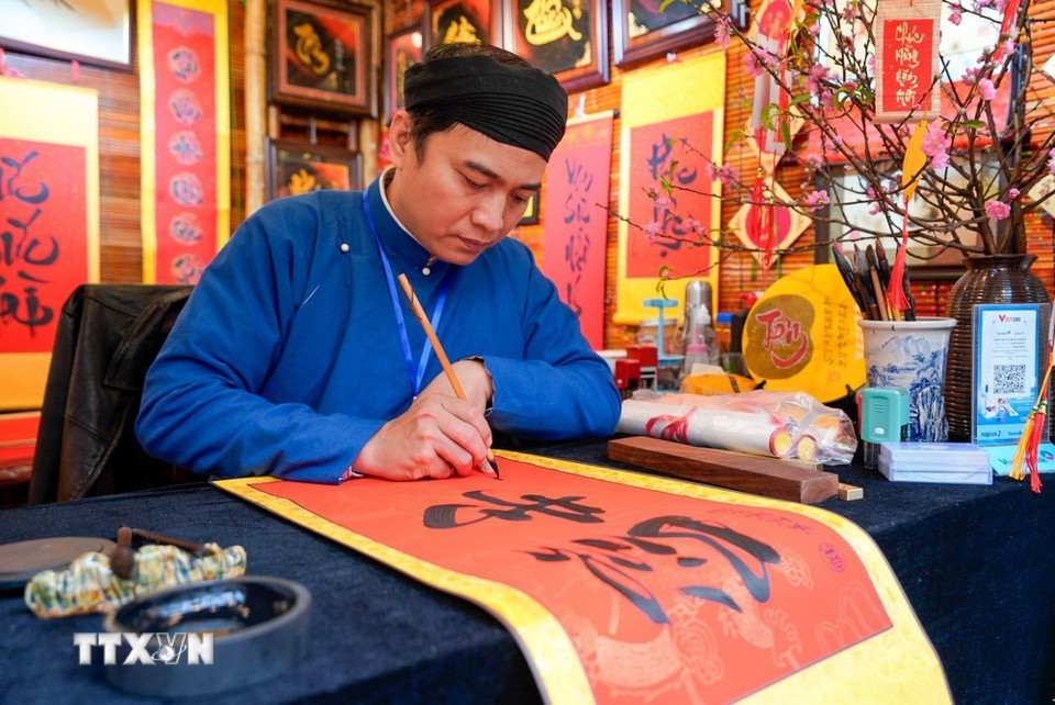 Cứ mỗi độ Xuân về, hình ảnh ông đồ bày mực tàu giấy đỏ lại trở nên quen thuộc, mang theo những con chữ gửi gắm lời chúc phúc, may mắn và tài lộc.(Ảnh: Khánh Hòa/TTXVN)