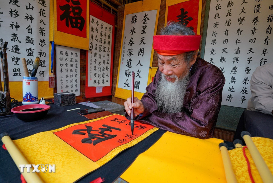Cứ mỗi độ Xuân về, hình ảnh ông đồ già bày mực tàu giấy đỏ lại trở nên quen thuộc, mang theo những con chữ gửi gắm lời chúc phúc, may mắn và tài lộc. (Ảnh: Khánh Hòa/TTXVN)
