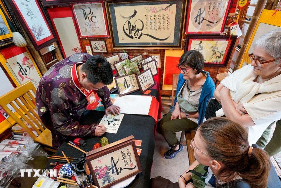 Du khách thích thú với phong tục xin chữ đầu năm của người Việt. (Ảnh: Khánh Hòa/TTXVN)