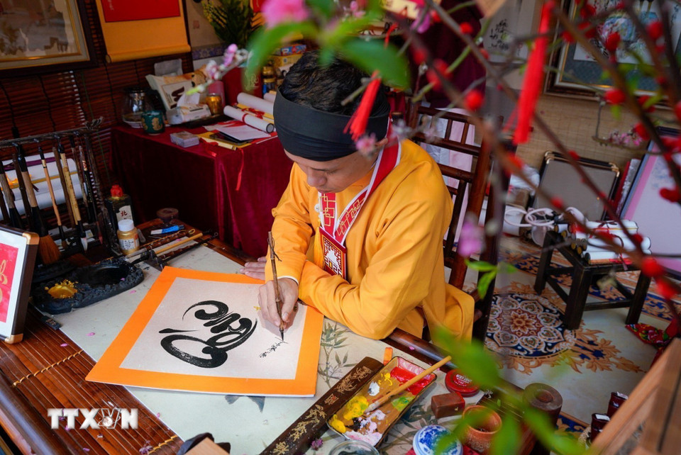 Cứ mỗi độ Xuân về, hình ảnh ông đồ bày mực tàu giấy đỏ lại trở nên quen thuộc, mang theo những con chữ gửi gắm lời chúc phúc, may mắn và tài lộc. (Ảnh: Khánh Hòa/TTXVN)