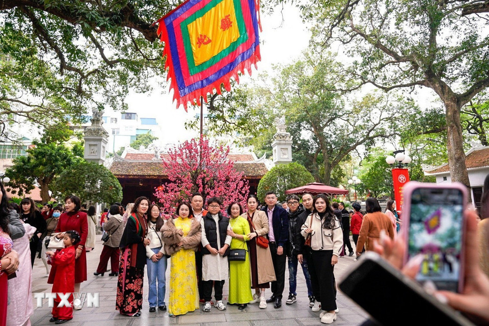 Người dân lưu lại khoảnh khắc đầu Xuân đi lễ đền Quán Thánh (trấn Bắc) ngày mùng 2 Tết Bính Ngọ. (Ảnh: Khánh Hòa/TTXVN)