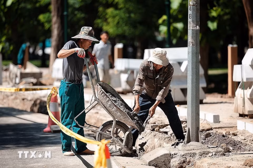 Công nhân xây dựng vẫn thi công trên vỉa hè dưới nắng nóng gay gắt. (Ảnh: Phạm Tuấn Anh/TTXVN)