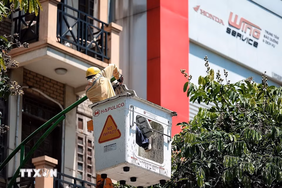 Công nhân Công ty TNHH Một thành viên Chiếu sáng và Thiết bị đô thị bảo dưỡng hệ thống chiếu sáng trên cao dưới nắng gắt trưa ngày 24/6. (Ảnh: Phạm Tuấn Anh/TTXVN)