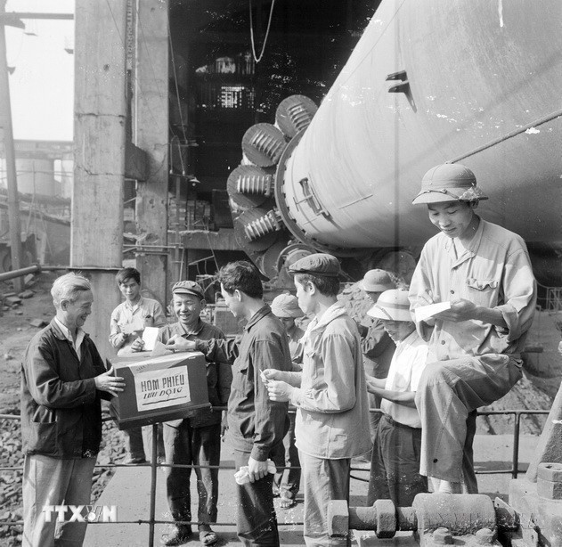 Trong điều kiện đất nước thống nhất, sự kiện lịch sử có ý nghĩa trọng đại là tổ chức thành công cuộc Tổng tuyển cử bầu Quốc hội chung của cả nước - Quốc hội khóa VI. Quốc hội đã quyết định những vấn đề quan trọng hàng đầu trong thời kỳ phát triển mới của dân tộc. Trong ảnh: Công nhân lò rung số 6 và 7, Nhà máy Xi măng Hải Phòng bỏ phiếu bầu đại biểu Quốc hội khóa VI tại nơi làm việc. (Ảnh: TTXVN)