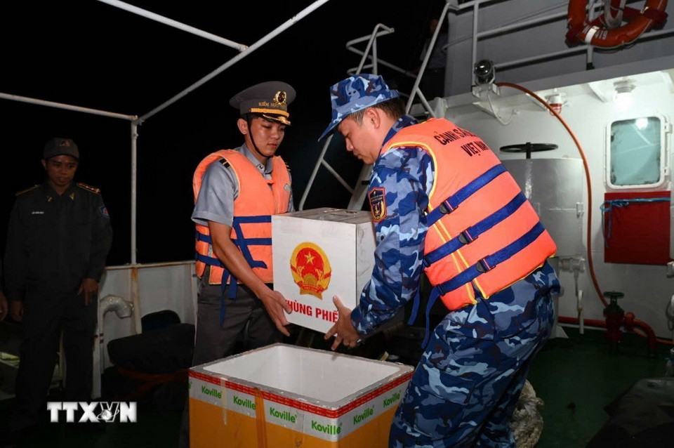 Đưa hòm phiếu vào thùng xốp để bảo quản khi Tổ bầu cử di chuyển từ tàu Kiểm ngư 260 sang tàu Cảnh sát biển 6008. (Ảnh: TTXVN phát)