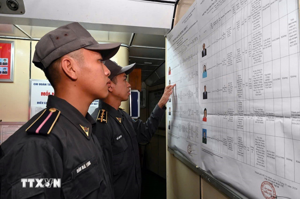 Cử tri tàu Cảnh sát biển 6008 tìm hiểu danh sách niêm yết các ứng cử viên. (Ảnh: TTXVN phát)