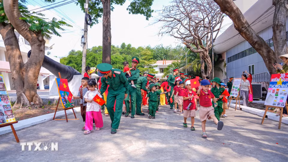 Cán bộ, chiến sỹ hướng dẫn các em nhỏ tìm hiểu về truyền thống quân đội thông qua hoạt động trực quan. (Ảnh: Minh Phú/TTXVN)