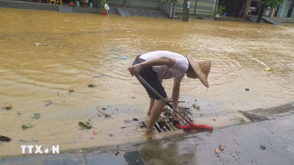 Người dân tổ 4 Duyên Hải, phường Lào Cai khơi thông cống rãnh thoát nước ngập úng. (Ảnh: Hương Thu/TTXVN)
