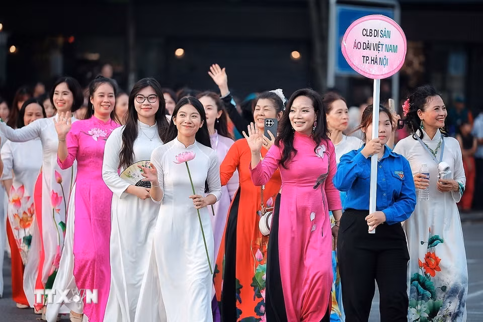 Các thành viên Câu lạc bộ Di sản Áo dài Việt Nam thành phố Hà Nội trong trang phục áo dài họa tiết sen tham gia đoàn diễu hành, góp phần tôn vinh vẻ đẹp áo dài Việt Nam. (Ảnh: Phạm Tuấn Anh/TTXVN)