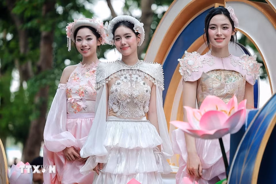 Các người mẫu trong trang phục lấy cảm hứng từ hoa sen trình diễn trên xe hoa, góp phần làm phong phú thêm ngôn ngữ nghệ thuật của chương trình. (Ảnh: Phạm Tuấn Anh/TTXVN)