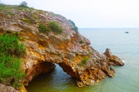 Nhìn từ trên cao, khu vực hang Mũi Trâu như một khuôn mặt người đang nhìn ra biển, cửa hang ngập trong nước khi thủy triều dâng cao. (Ảnh: Xuân Tiến/TTXVN)