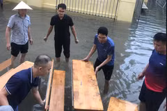 Các thầy cô giáo Trường Tiểu học Nam Trung Yên đã kê bàn ghế làm cầu giúp phụ huynh đón con, học sinh không bị dầm nước. (Ảnh: PHCC)