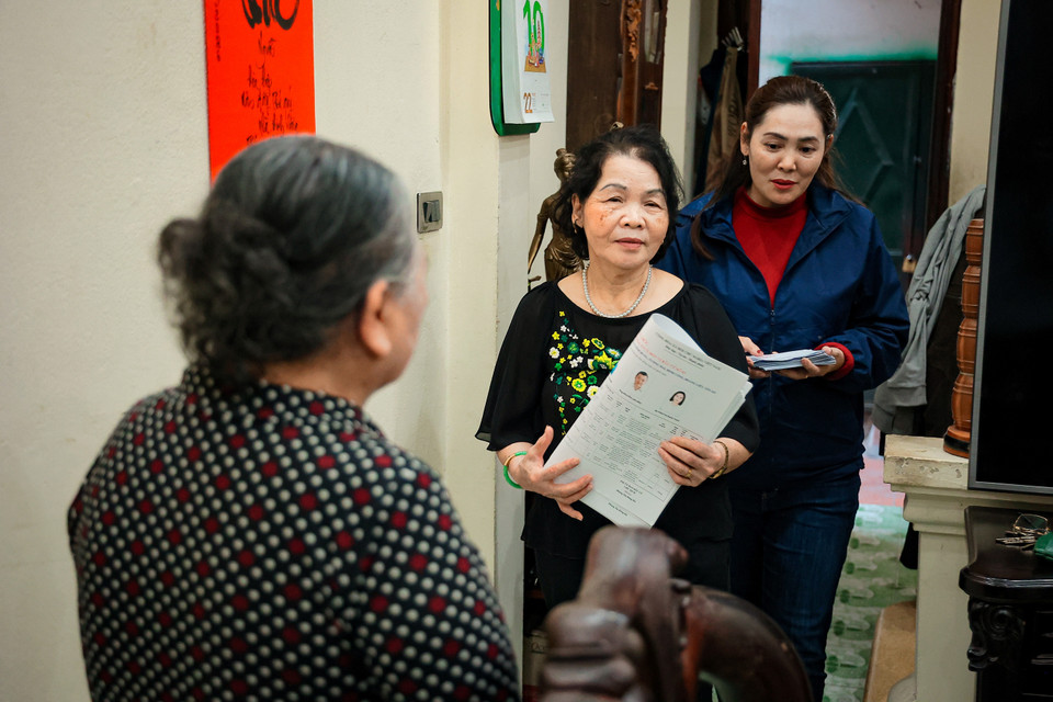 Không quản ngại mưa nắng hay những con ngõ lắt léo của Thủ đô, các nữ cán bộ cơ sở vẫn miệt mài với công việc phát thẻ cử tri và tuyên truyền bầu cử. (Ảnh: Hoài Nam/Vietnam+)