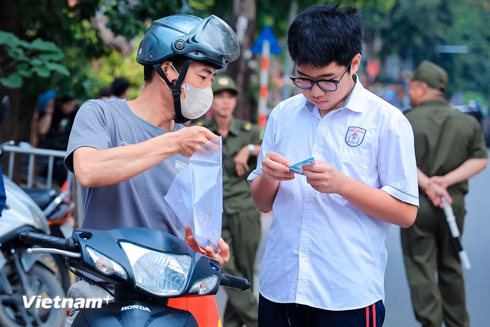 Dù thời tiết Hà Nội có những ngày nắng như đổ lửa hay bất chợt đổ cơn mưa rào, các điểm thi lúc nào cũng đông từ rất sớm. Từ 6h sáng, những chiếc xe máy chở theo ước mơ của cả gia đình đã nối đuôi nhau đổ về cổng trường cùng những lời động viên. (Ảnh: Hoài Nam/Vietnam+)