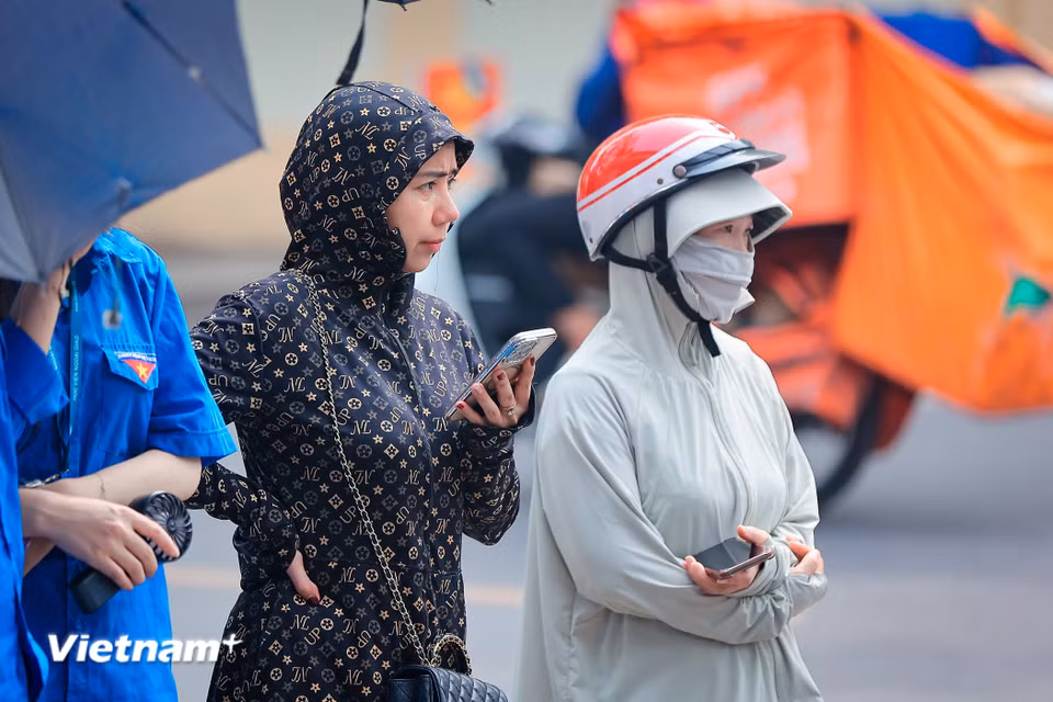 Sức nóng không chỉ nằm ở trong phòng thi mà còn lan tỏa mạnh mẽ ra ngoài cổng trường — nơi hàng vạn phụ huynh đang nhấp nhổm đợi con. (Ảnh: Hoài Nam/Vietnam+)