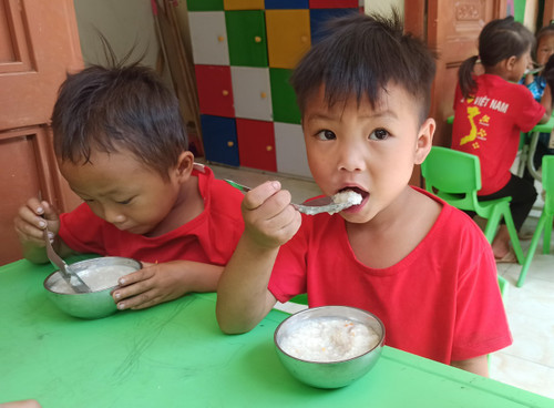 Học sinh điểm trường Bản Là ăn bữa phụ chiều. (Ảnh: Phạm Mai/Vietnam+) z5488221227188_f1ce9e5f0ac71da98194dfe2d6c5a74c.jpg