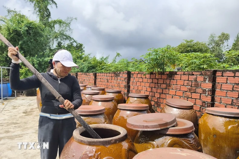 Chị Trương Thị Bốn (Chủ cơ sở Nước mắm Cửa Khe Bốn Thái) cho biết mắm phải ủ trên 12 tháng thì mới đậm vị, thơm ngon. (Ảnh: Quốc Dũng/TTXVN)