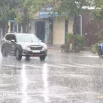 Người dân đi lại trong mưa lớn. (Ảnh: Nguyên Lý/TTXVN)