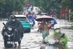 Chân dốc Minh Khai mênh mông nước, người dân gặp nhiều khó khăn khi cố gắng di chuyển. (Ảnh: Thanh Tùng/TTXVN)
