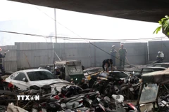 Lực lượng chức năng tiếp cận hiện trường vụ cháy bãi xe tại khu vực chân cầu Vĩnh Tuy (Hà Nội). (Ảnh: Vũ Quang/TTXVN)