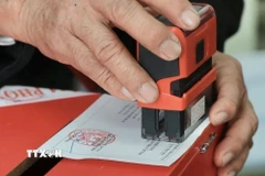 Thành viên tổ bầu cử đóng dấu hoàn thành bỏ phiếu lên thẻ cử tri. (Ảnh: Minh Quyết/TTXVN)