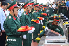 Thực hiện nghi thức an táng hài cốt liệt sỹ. (Ảnh: K GỬIH/TTXVN)