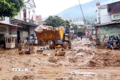 Máy xúc được huy động để hỗ trợ san gạt, thu gom bùn đất, cành cây, rác bị tràn về trong đợt lũ vừa qua tại xã Sông Mã. (Ảnh: Quang Quyết/TTXVN)