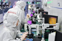 Các kỹ thuật viên làm việc trong xưởng sản xuất chip. (Nguồn: Xinhua)
