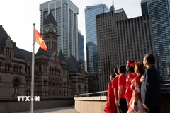 Đại diện cộng đồng người Việt chào cờ tại buổi lễ. (Ảnh: TTXVN phát)