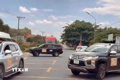 2 chiếc xe ngang nhiên đậu so le trên cả 2 chiều, chặn đường để đoàn xe doanh nhân băng qua Quốc lộ 20. (Ảnh: TTXVN phát)