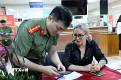 Cán bộ, chiến sỹ Cục quản lý xuất nhập cảnh, Bộ Công an hướng dẫn người nước ngoài làm thủ tục cấp tài khoản định danh điện tử. (Ảnh: Phạm Kiên/TTXVN)