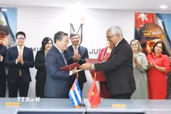 Bộ trưởng Nguyễn Hải Ninh và Bộ trưởng Oscar Manuel Silvera Martínez trao đổi kiện sau lễ ký. (Ảnh: Việt Hùng/TTXVN)