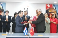 Bộ trưởng Nguyễn Hải Ninh và Bộ trưởng Oscar Manuel Silvera Martínez trao đổi kiện sau lễ ký. (Ảnh: Việt Hùng/TTXVN)