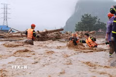 Lực lượng cứu nạn cứu hộ Công an tỉnh Lai Châu căng dây giữa dòng nước lũ đưa người dân xã Mường Than ra khỏi vùng bị cô lập nguy hiểm đến nơi ở an toàn. (Ảnh: Quý Trung/TTXVN)